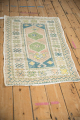 A distressed Turkish Oushak rug from an angle, showing its faded double medallion and border.