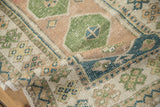 Hand-knotted texture of a distressed Turkish rug with geometric patterns in sandalwood, green, and blue.