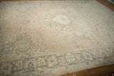 Distressed Tabriz carpet's dusty rose field, showing sprawling vines and faded floral motifs.