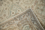Distressed Tabriz carpet corner, showing woven foundation, original selvage, and worn beige, rose, silver pile.