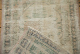 Corner of vintage distressed Oushak rug showing worn cream pile and woven reverse with pink selvage.