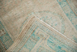 Secured side cord and hand-knotted texture of a distressed Oushak rug in cream and turquoise.