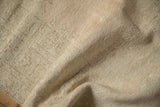 Close-up of the rug's reverse, showing the hand-knotted foundation and sandy texture.