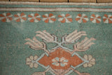 Vintage Distressed Oushak rug section: mint green field, terracotta finned floral, pinwheel border.