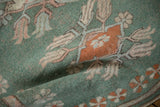 Folded vintage Oushak rug highlighting distressed texture, mint green field, and terracotta floral motifs.