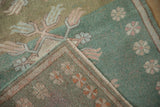 Folded corner of Oushak rug shows abrashed mint green field with pinwheel motifs and finned florals.