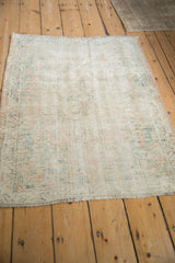 Angled view of a distressed Oushak rug highlighting its faded pattern and textured, time-worn surface.