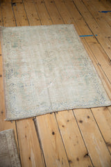 Angled view of a distressed Oushak rug revealing its textural, time-softened wear and muted palette.