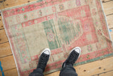 A vintage Oushak prayer rug with distressed texture shown on the floor for scale.