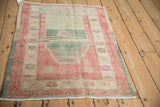Vintage Oushak rug seen from an angle, highlighting its distressed texture and prayer niche.