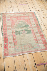 Vintage Oushak prayer rug from a low angle, showing its distressed pile and soft patina.