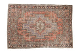 Decorative distressed vintage Oushak rug, pale brick red field, faded aubergine medallion.