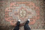 Textured pile of vintage distressed Oushak rug with brick red, dusty aubergine, and ivory.