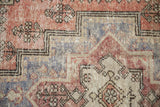 Distressed Oushak rug's intricate stepped pattern and floral motifs in brick red, blue, ivory.