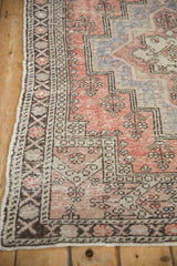 Distressed Oushak rug corner: floral border, stepped medallion, brick red, ivory, chocolate tones.
