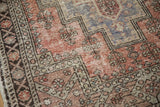 Distressed Oushak rug detail: worn pile, brick red field, blue-grey tones, geometric border.