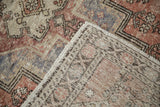 Distressed vintage Oushak rug: worn brick red pile, hand-knotted foundation, and secured edge.