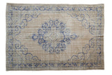 Distressed vintage Oushak carpet with a blue scalloped medallion on a worn, antique ivory open field.