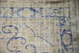Close-up of the distressed Oushak corner showing worn pile, ivory ground, and cobalt blue spandrels.