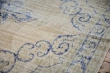 Close-up on the distressed texture of the vintage Oushak carpet, showing wear to the knot heads.