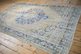 Angled view of a distressed Turkish Oushak carpet showing its soft texture and blue medallion.