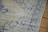 Wear to the foundation showing visible knot heads on a distressed Oushak with blue scrolled leaves.