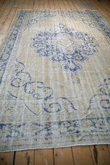 Low angle view of a distressed Oushak highlighting its visible weaver lines and worn, low pile.