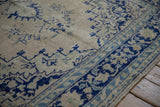 Distressed Oushak corner with stepped cobalt blue motifs showing an even, low-pile texture.