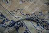 Distressed low-pile weave of a vintage Oushak carpet with visible ivory and cobalt blue knot heads.