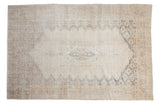 Distressed vintage Sparta carpet, softened ivory and beige, faded blue medallion design.