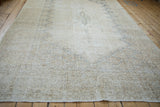 Distressed border of a vintage Sparta carpet with faded ivory, beige, and dusty blue patterns.