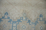 Distressed vintage Sparta carpet close-up: exposed foundation, visible repair, and blue geometric pattern.