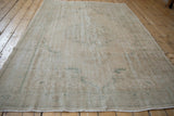 Distressed Oushak carpet close-up, highlighting visible weaver delimiters in beige and sea foam green.