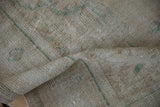 Distressed texture of a vintage Oushak carpet, showing visible foundation and sea foam green accents.