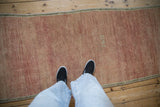 Distressed vintage Oushak runner showing pale ruby red, rose, and tangerine abrash underfoot.