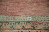 Distressed vintage Oushak runner detail: abrashed dusty rose field and geometric pale green, tangerine border.