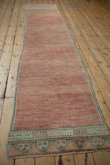 Geometric border of a distressed Oushak rug runner in olive green and tangerine tones.