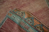 Distressed vintage Oushak runner pile with abrashed rose field and geometric border.