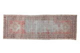 Distressed vintage Oushak runner, faded rose and aubergine hues, with visible foundation wear.