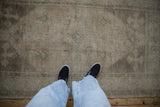 A view down at the soft, distressed texture and muted tone-on-tone pattern of a vintage Oushak rug.