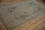 Side angle view of a distressed Oushak rug highlighting the soft patina and even wear of its low pile.
