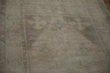 Angled close-up of the distressed Oushak rug's low, even pile revealing the knot heads.