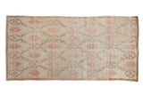 Vintage distressed Oushak rug runner with repeating floral panels in dusty mauve and beige on an ivory ground.