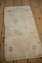 Distressed Oushak rug corner, showing low pile and faded seafoam green motifs.