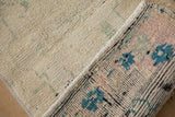 Distressed vintage Oushak rug's ivory foundation with worn seafoam green and pink pile.