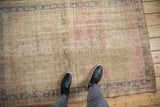 Distressed Oushak rug texture showing heavy abrashes, antique ivory, and vivid pink with blue hints.