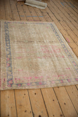 Distressed vintage Oushak rug with worn texture, pale blue border, and fuchsia abrashes.