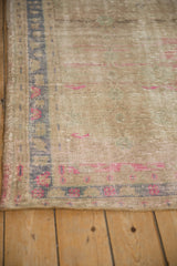 Distressed Oushak rug corner highlighting worn texture, dusty blue border, and vibrant fuchsia motifs.