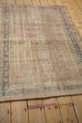 Distressed vintage Oushak rug corner showing textured wear, fuchsia, and blue tones.
