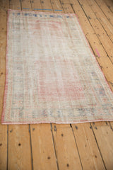 Distressed vintage Oushak rug showing worn pile, visible foundation, muted ivory and pink.